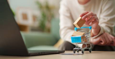 Vrouw voegt miniatuurverpakking toe aan winkelwagen naast de laptop